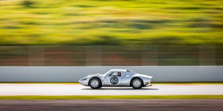 A classic vintage race car number 60 zooms on a track, showcasing speed and motion blur.