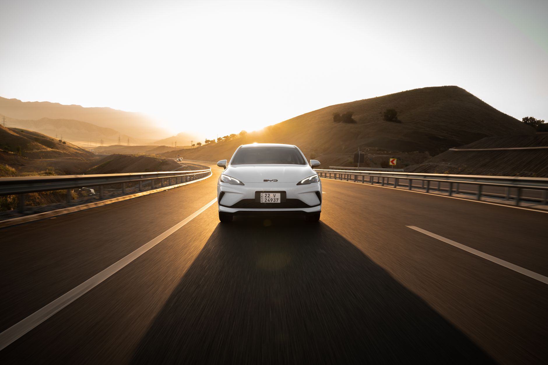 Voiture électrique roulant sur une autoroute panoramique au coucher du soleil, mettant en valeur le design automobile moderne et le voyage durable.