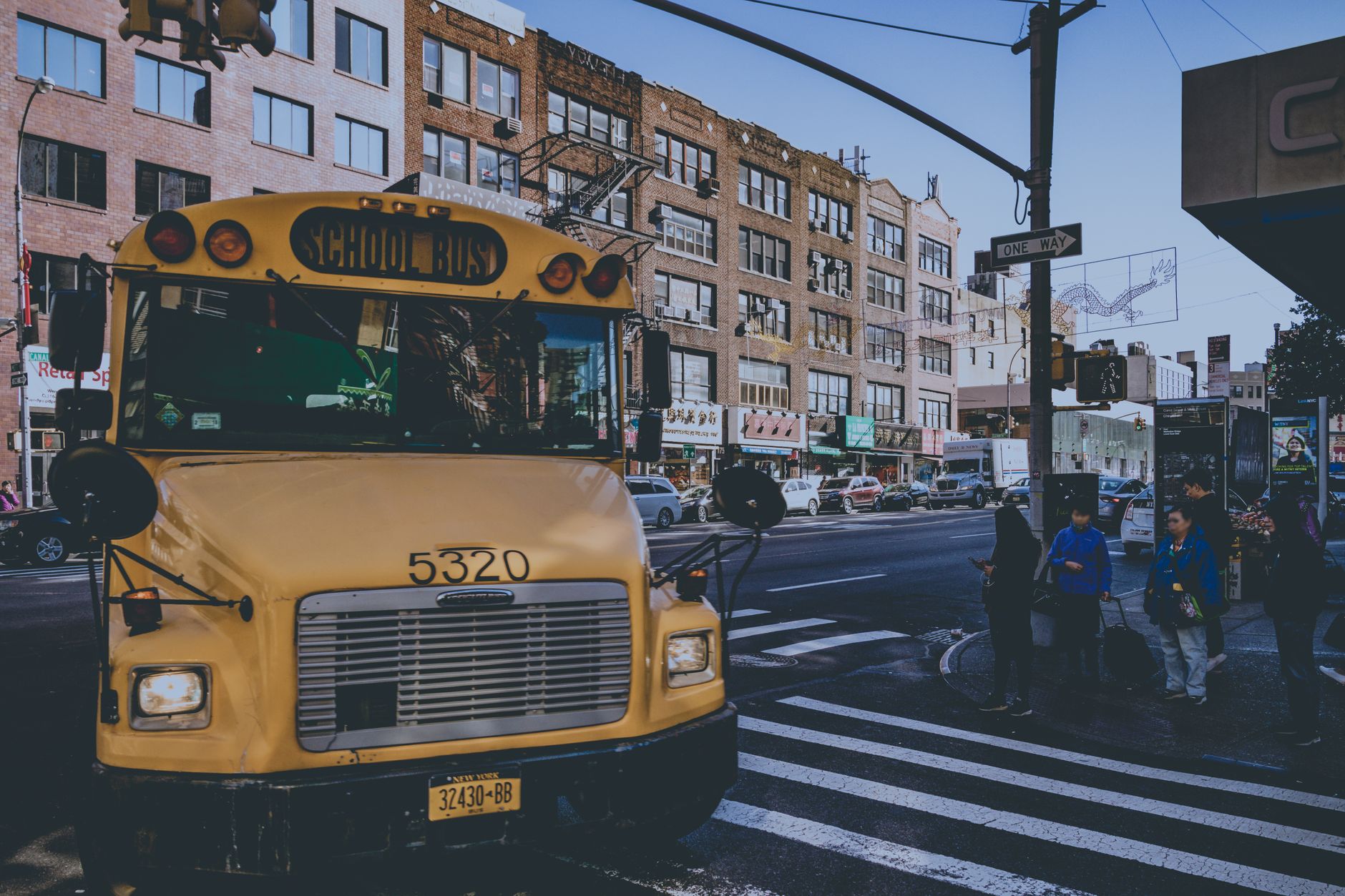 Un bus scolaire jaune dans une rue de ville animée avec des piétons à New York.