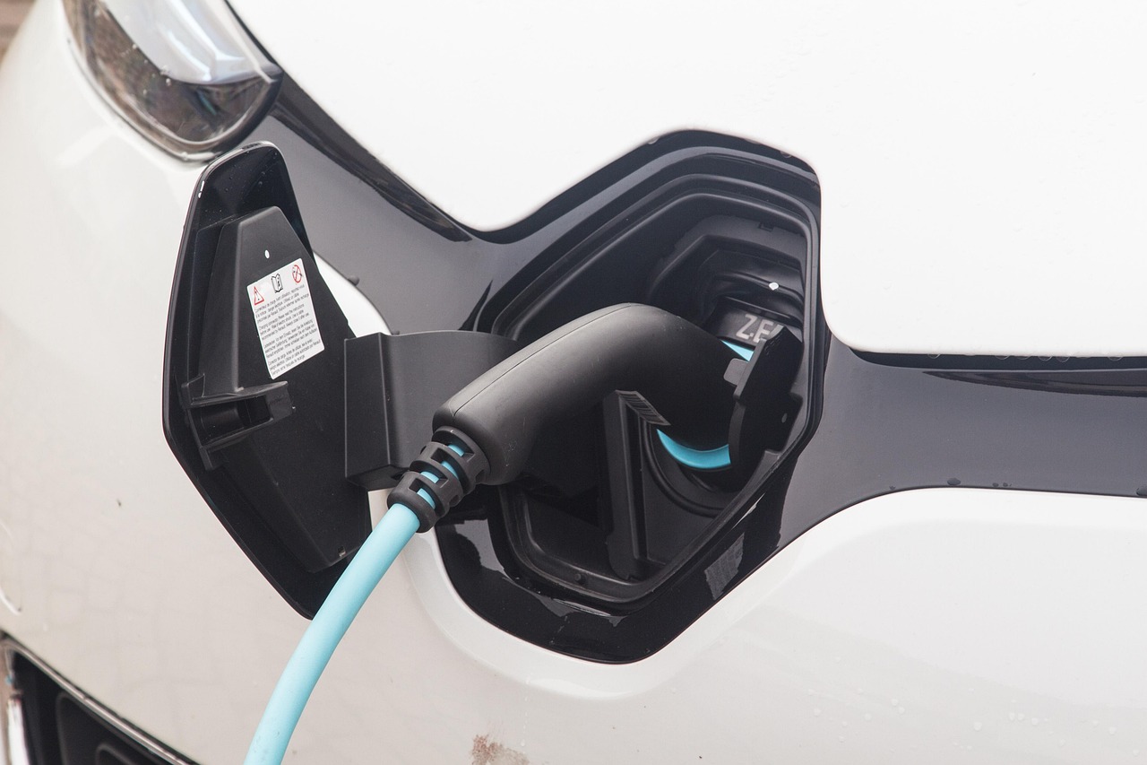 Un câble de recharge bleu branché dans le port d’une voiture électrique blanche